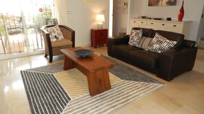 A living room with a sofa, armchair, coffee table, and a lamp.