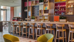 Een barruimte met houten stoelen, een bar en flessen op de planken.