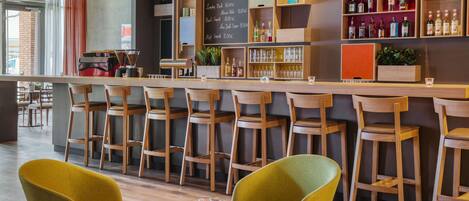 Una zona de bar con sillas de madera, una barra y estantes con botellas.