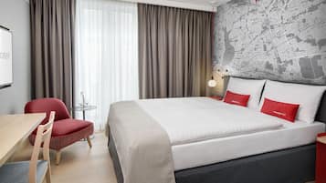 Habitación de hotel con una cama grande, un escritorio, una silla y un mapa en la pared.