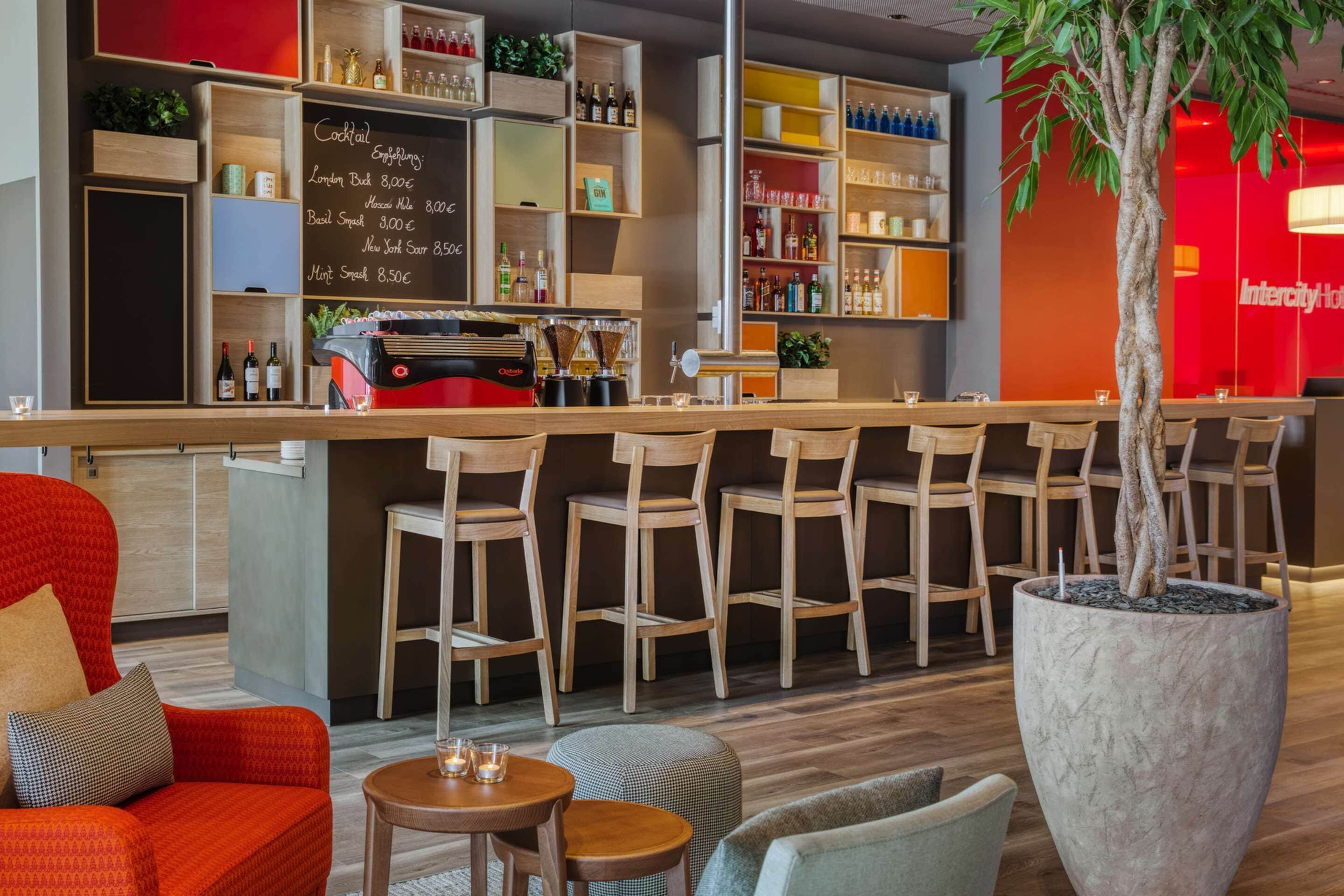 Una zona de bar con sillas de madera, una barra y una planta grande en maceta.