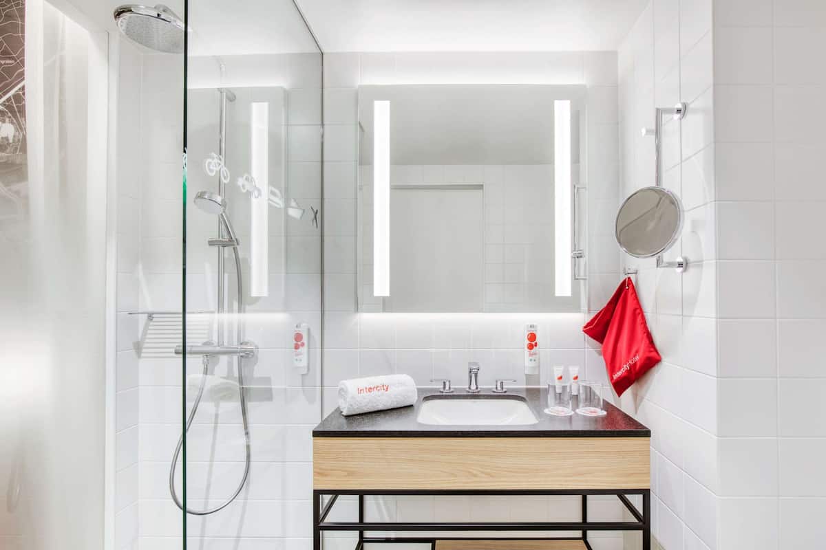 Een moderne badkamer met een douchecabine van glas, een houten wastafelmeubel en een spiegel.
