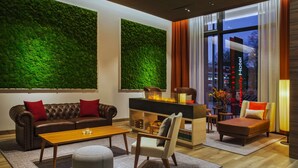 Een moderne woonkamer met een groene muur, leren bank, houten salontafel en een open haard.