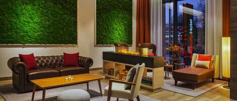 A modern living room with a green wall, leather sofa, wooden coffee table, and a fireplace.