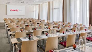 Un salón de conferencias en el Hotel Intercity con filas de mesas, sillas y pantallas de presentación.