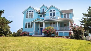 A two-story house with a front porch, a small balcony, and a well-maintained lawn. - Soundside, Private Pool, Rec Room, Hot Tub, CC204, Aqua Holic (Corolla)