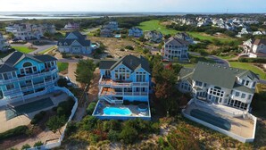 A residential area with multiple houses, including a large house with a swimming pool and a golf course in the background. - Soundside, Private Pool, Rec Room, Hot Tub, CC204, Aqua Holic (Corolla)