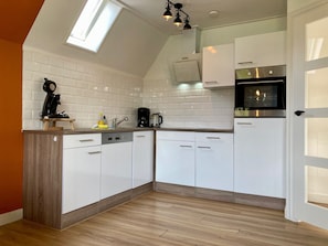A kitchen with white cabinets, a coffee maker, a kettle, and a clock on the counter.