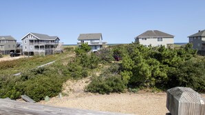 Ein Küstenwohngebiet mit Häusern, einer Holzterrasse und freiem Blick auf den Strand.