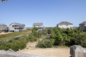 A coastal residential area with houses, a wooden deck, and a clear view of the beach.
