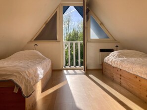 Ein Zimmer mit zwei Betten, einem Balkon und einem Fenster.
