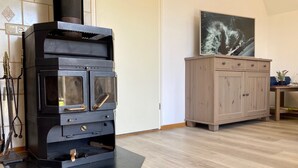 A modern kitchen with a black stove, wooden cabinets, and a tiled backsplash. - Cozy Holiday Home by the Dike in a Quiet Location at Lauwersmeer (Anjum)