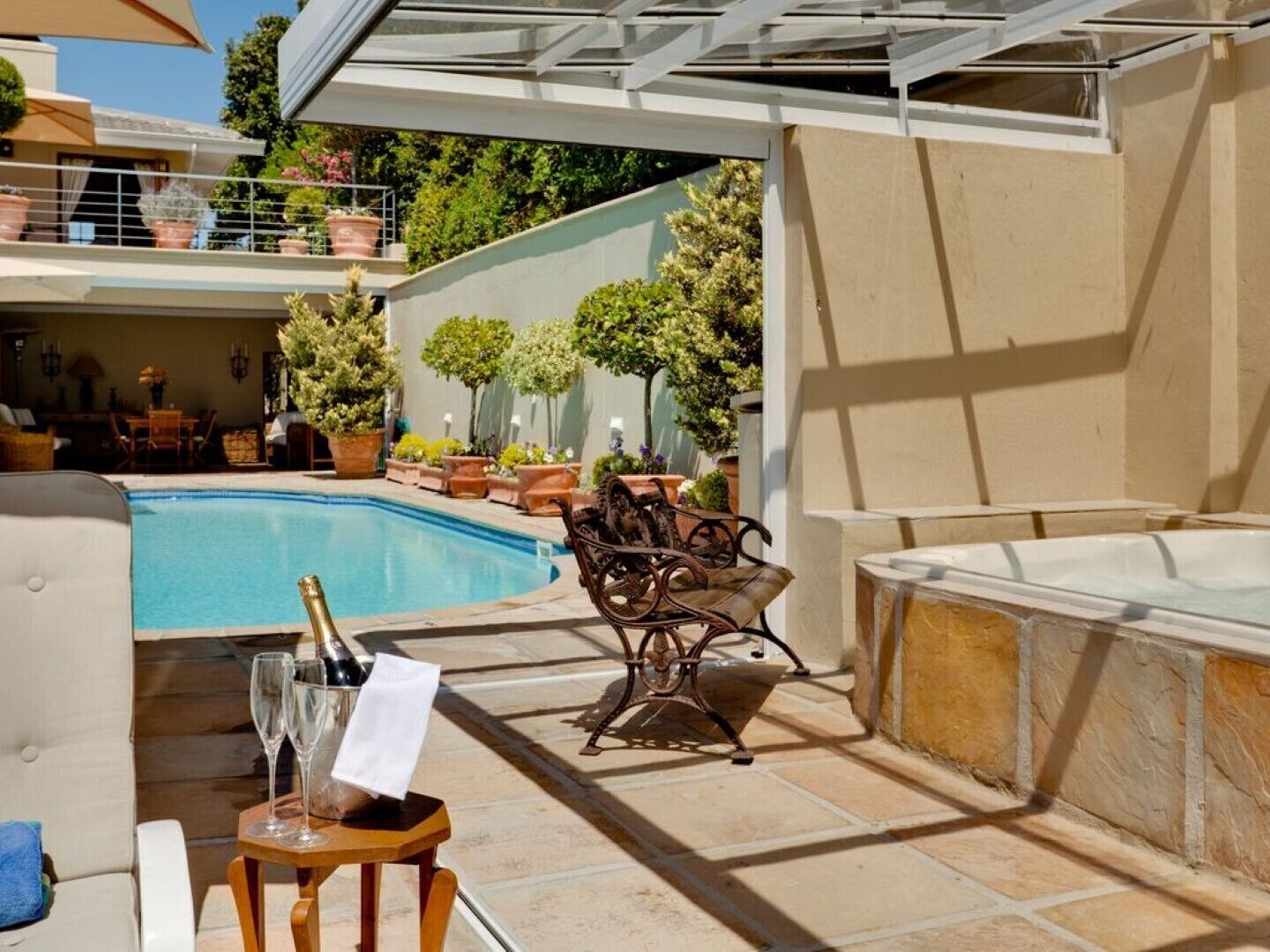 Et poolområde med jacuzzi, udendørs møbler og et bord med champagneglas.