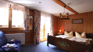Quarto com painéis de madeira, uma cama, uma cadeira e um radiador.