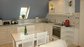 Eine moderne Küche mit weißen Schränken, einem Esstisch mit Stühlen und einem eingebauten Backofen.