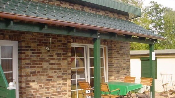 A brick building with a green roof and a covered patio area. - Haus Koralle Wohnung Rechts (Boltenhagen)