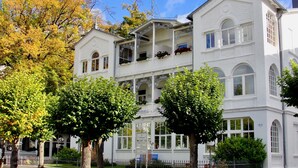 Un immeuble blanc à plusieurs étages, doté de balcons, de grandes fenêtres et d’une enseigne indiquant « Hôtel ».