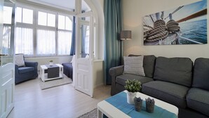 Un salon moderne avec un canapé, une table basse et un tableau représentant un bateau accroché au mur.