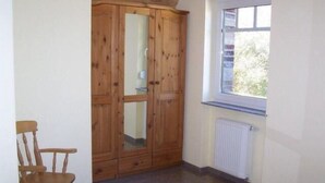 Ein Zimmer mit Holzschrank, Fenster und Heizkörper.