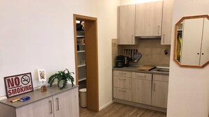Een compacte keuken met licht houten kastjes, een aanrecht met een koffiezetapparaat, en een 'No Smoking' bord.