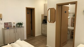 Een hotelkamer met een bed, een bureau, een rookvrij bordje, een spiegel en een badkamer die door een open deur zichtbaar is.