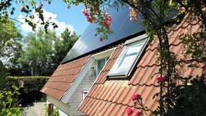 A house with a sloped roof, a visible window, and a pathway leading to the entrance.