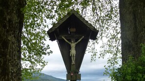 A wooden crucifix with a view of a mountainous landscape in the background. - Ehlershus (Reit im Winkl)