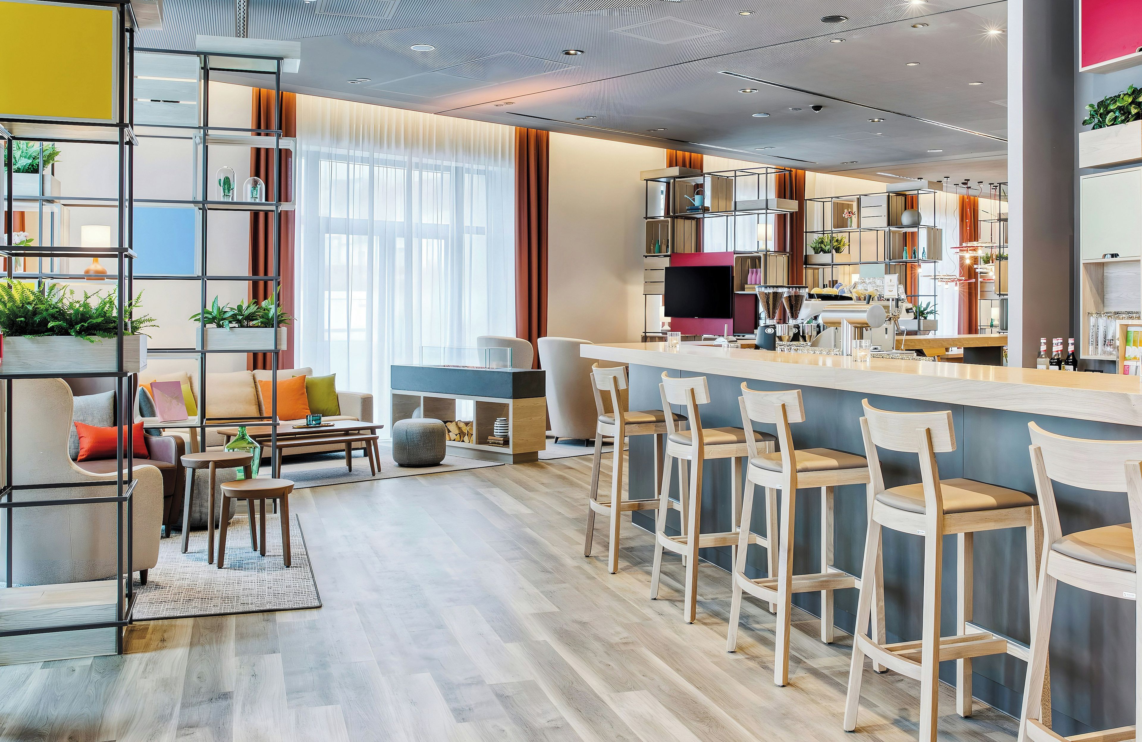 A modern kitchen with a bar area, wooden flooring, and a seating area with a sofa and chairs.