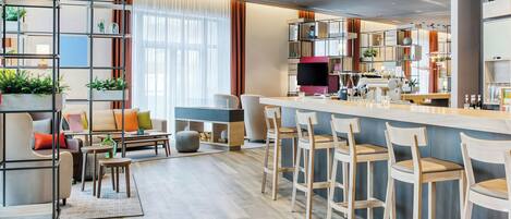 Una cocina moderna con barra, piso de madera y una zona de estar con sofá y sillones.