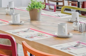 A dining table set with white plates, silverware, and a potted plant. - Leonardo Hotel Hannover City Center (Hannover)