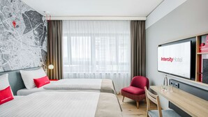 Habitación de hotel con dos camas, una silla roja, un escritorio con televisor y un mapa en la pared.