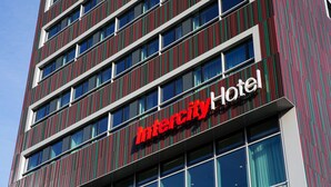 Un moderno edificio de hotel con fachada a rayas verticales y un llamativo letrero que dice 'Intercity Hotel'.