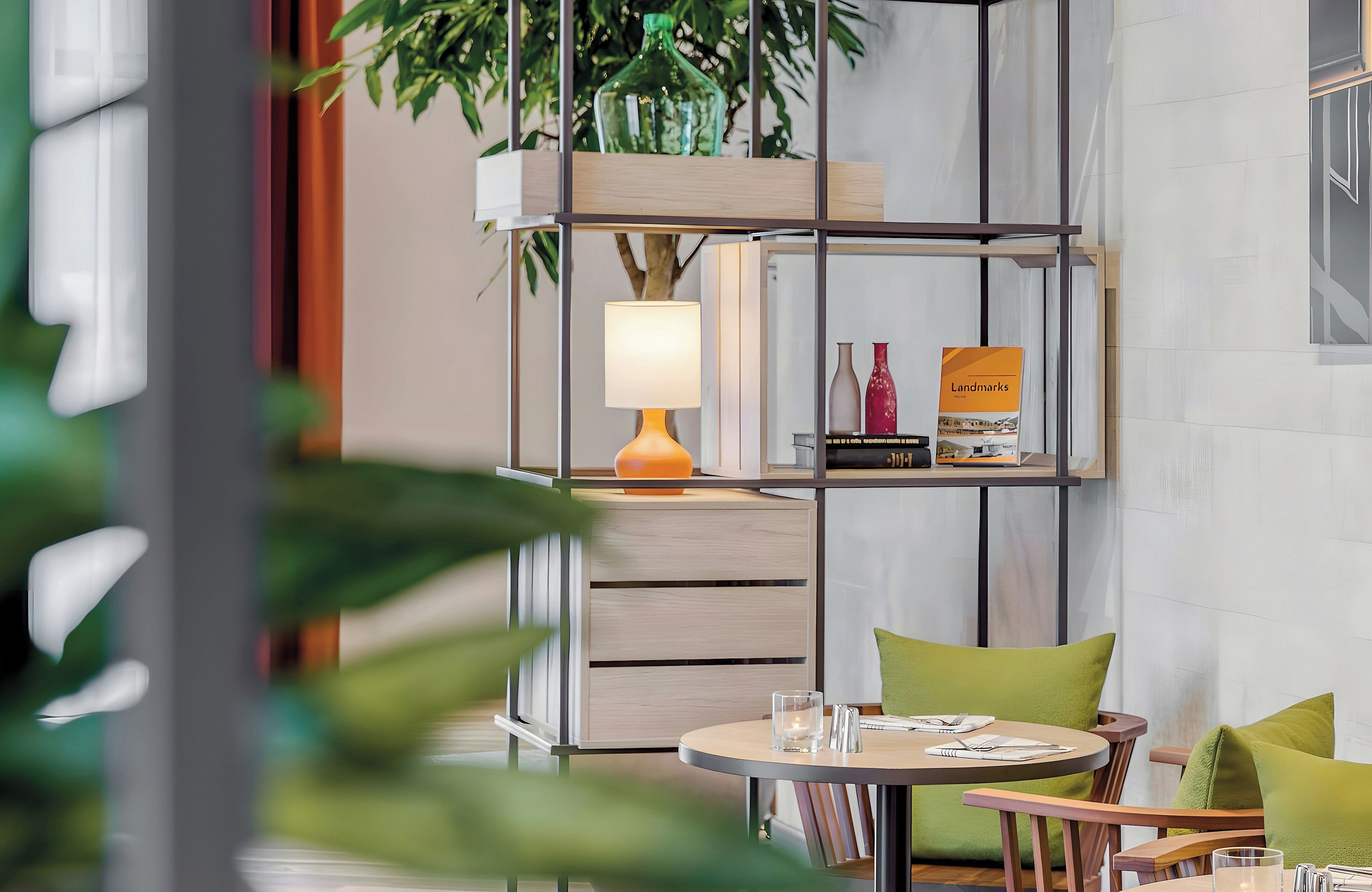 A modern interior with a round table, green cushions, a lamp, and a bookshelf.
