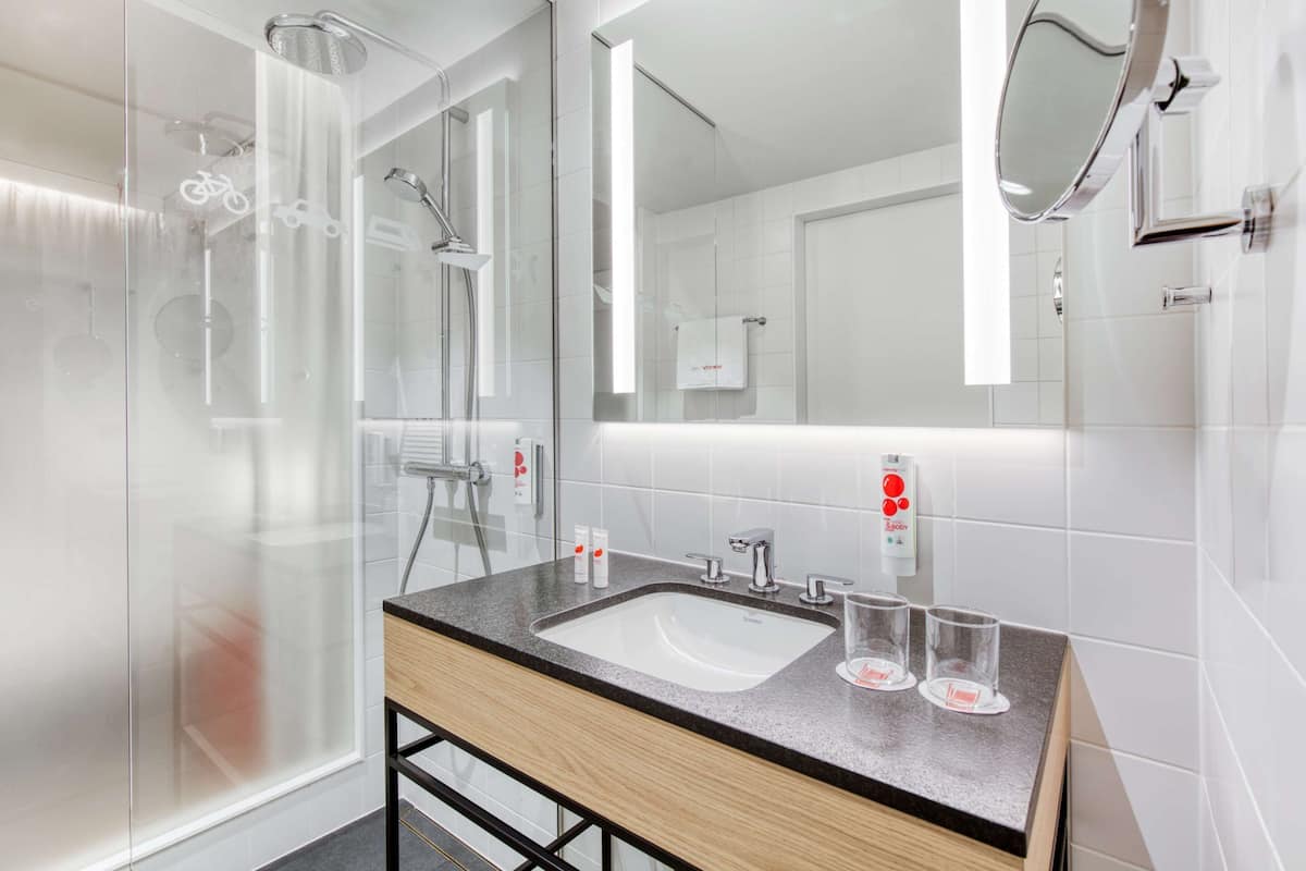 A modern bathroom with a glass shower enclosure, a wooden vanity with a sink, and a large mirror.