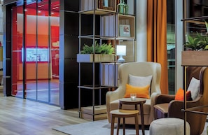 A modern interior with a seating area, a bookshelf, and a television screen. - Leonardo Hotel Hannover City Center (Hannover)