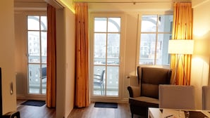 A hotel room with a sofa, armchair, dining table, and curtains. - Urlaub und Erholung mit Charme und Stil auf Rügen (Sellin)