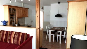 A compact living space with a kitchen, dining area, and a red sofa. - Ferienwohnung "rosenrot" auf dem Ferien + Bauernhof Nilson in Inselmitte (Fehmarn)