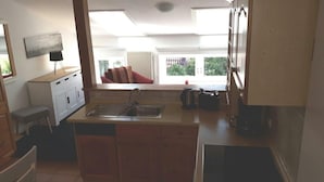 A compact kitchen with a sink, stove, and cabinets. There is a window with a view of greenery outside. - Ferienwohnung "rosenrot" auf dem Ferien + Bauernhof Nilson in Inselmitte (Fehmarn)
