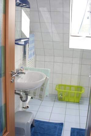 A bathroom with a sink, mirror, and a green laundry basket.