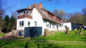 A two-story house with a sloped roof, a stone wall, and a garage.