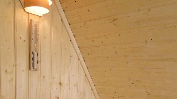 Una sauna de madera con bancos y un calentador de piedra.