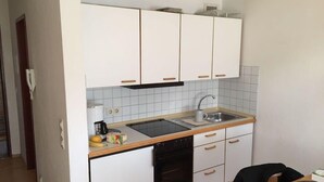 Eine kleine Küche mit weißen Schränken, einem schwarzen Geschirrspüler und einer Holz Arbeitsplatte.