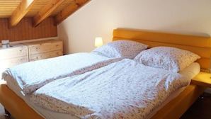 Ein Doppelbett mit floralem Bettzeug in einem Zimmer mit Holzbalken und einem Oberlicht.