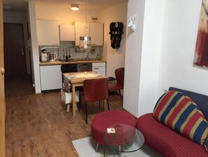 A compact living space with a kitchenette, a dining area, and a sofa. - Sehnsucht Allgäu (Oberstaufen)