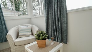 Una habitación con un sofá color beige, una mesita de madera con una planta en maceta y una pequeña estatua decorativa de un pájaro.