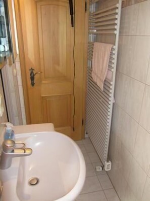 A bathroom with a wooden door, a white sink, and a towel rack with a towel. - Aalener Haus Wohnung 3 (Oberstdorf)