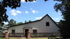 Ein weißes Gebäude mit Satteldach, Ziegelveranda und Metallzaun.