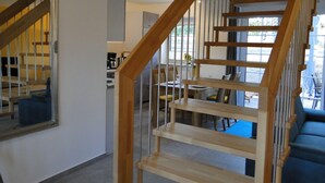 A staircase with wooden railings leading to a dining area with a table and chairs. - Bispinger Heidezauber - Haus Hartriegel (Bispingen)