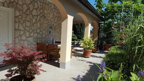 A stone building with a covered patio area, outdoor seating, and potted plants. - Apartment-studio Ginkgo A1 (Medulin)