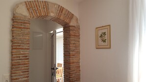 An arched brick doorway leading to a room with a framed botanical illustration on the wall. - Apartment-studio Ginkgo A1 (Medulin)